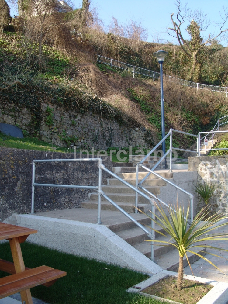 Interclamp key clamp handrail installed on a seaside town's coastal viewing are, blending functionality with the picturesque sea and sky backdrop